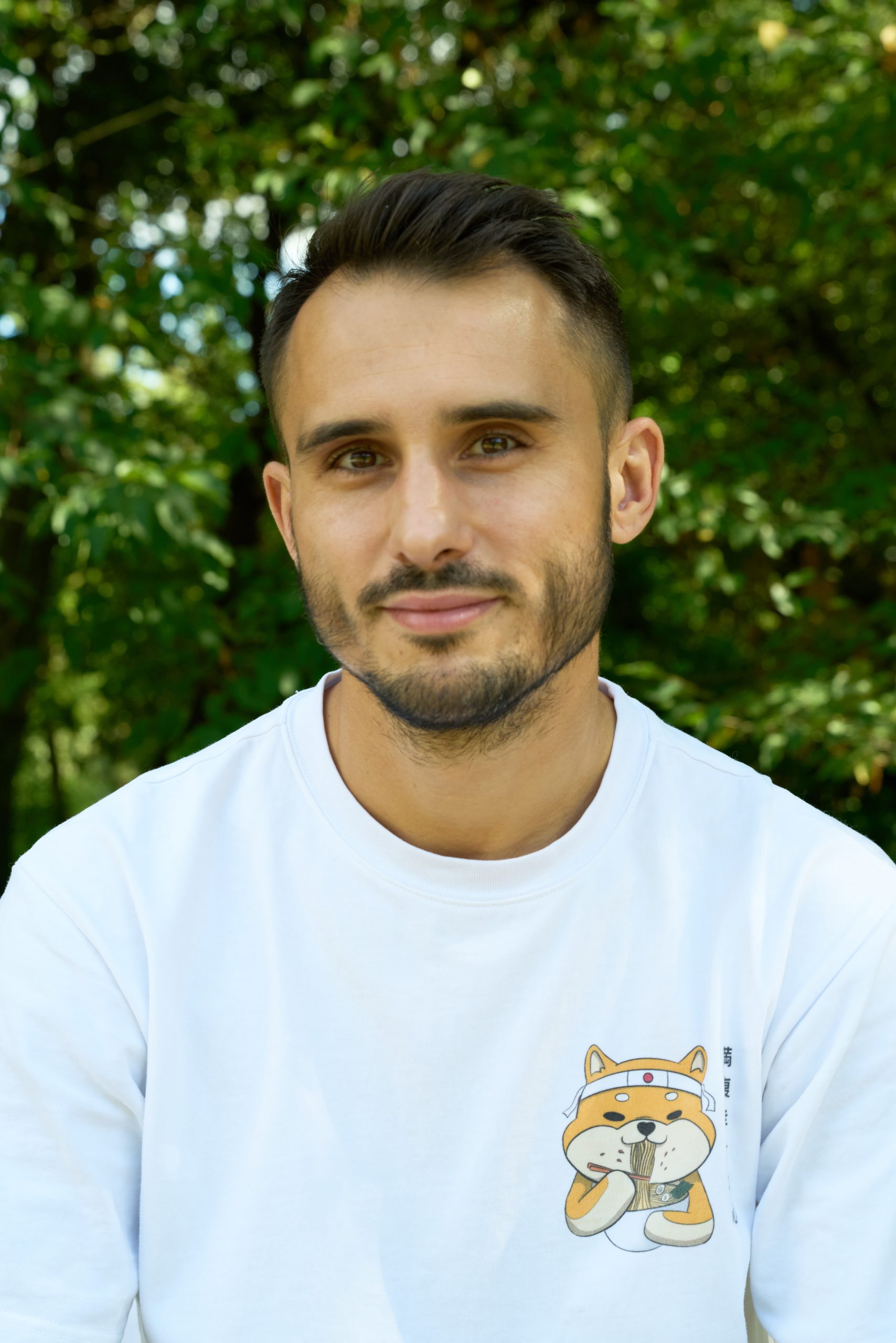 Portrait de Robin Viciana, photographe et fondateur, souriant devant un fond de verdure naturel.